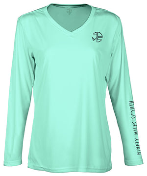front view of a ladies sea foam green v-neck performance shirt with 90 Miles South Round left chest logo and right sleeve copy saying “90 Miles South”