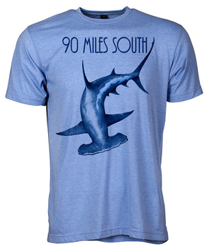 Front view of short sleeve heather blue tee shirt with dark blue artwork of 90 Miles South Hammerhead Shark