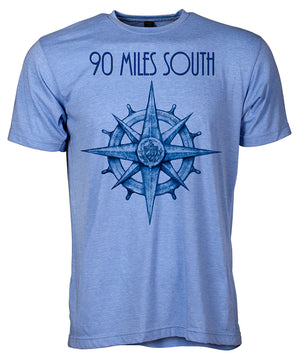 Front view of short sleeve heather blue tee shirt with dark blue artwork of 90 Miles South compass