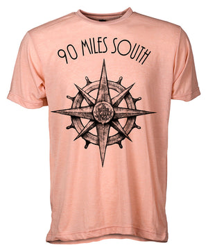 Front view of short sleeve heather peach tee shirt with black artwork of 90 Miles South compass